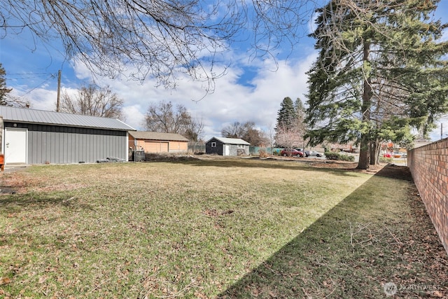 view of yard featuring fence, a pole building, and an outdoor structure