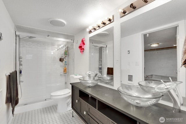 bathroom featuring a sink, double vanity, a stall shower, and a textured ceiling
