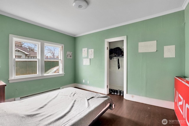 bedroom featuring a closet, ornamental molding, wood finished floors, a baseboard radiator, and baseboards