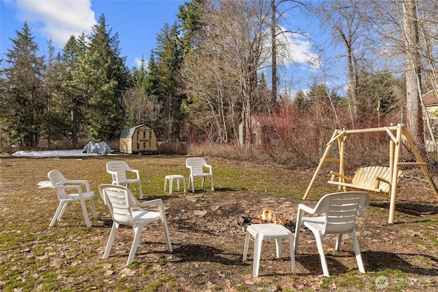 1081 Wapiti Dr, Cle Elum, WA 98922 - view of yard featuring a shed, a playground, an outdoor structure, an outdoor fire pit, and view of wooded area