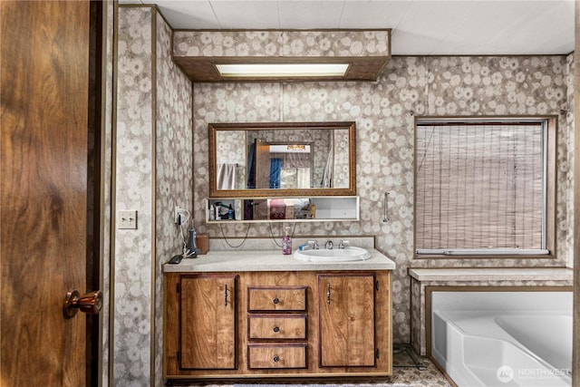 full bathroom featuring wallpapered walls, a bath, and vanity