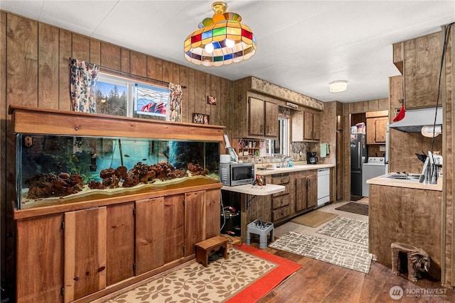 kitchen with light wood-style flooring, stainless steel microwave, freestanding refrigerator, white dishwasher, and light countertops