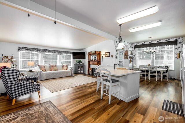 dining area featuring a wealth of natural light, an inviting chandelier, lofted ceiling with beams, and dark wood finished floors