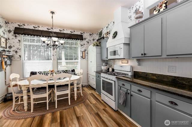 kitchen featuring wallpapered walls, gray cabinetry, white appliances, and a notable chandelier