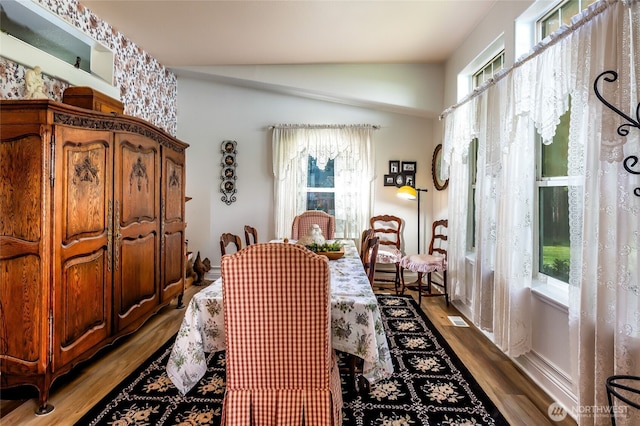 dining area featuring visible vents, wood finished floors, and lofted ceiling