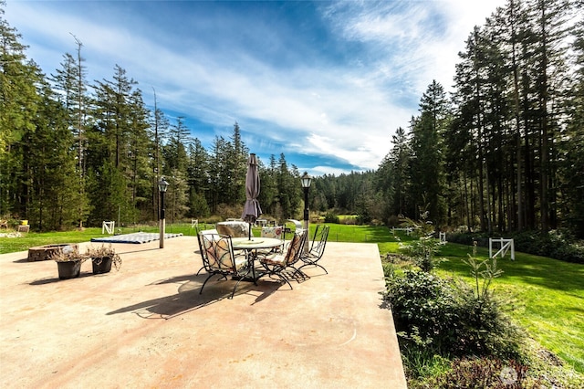 view of patio featuring outdoor dining space and a forest view
