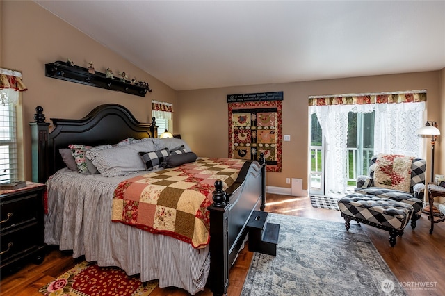 bedroom featuring access to outside, baseboards, vaulted ceiling, and wood finished floors