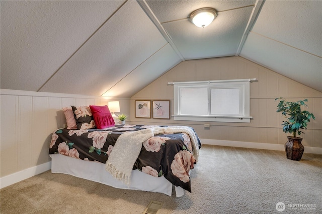 bedroom featuring lofted ceiling, carpet flooring, and a textured ceiling