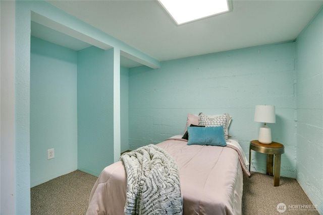carpeted bedroom with concrete block wall