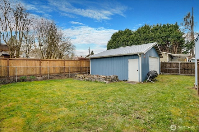 view of yard with a fenced backyard, an outbuilding, and a garage