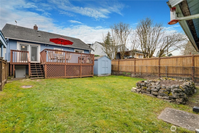 view of yard featuring an outdoor structure, a fenced backyard, a shed, and a deck