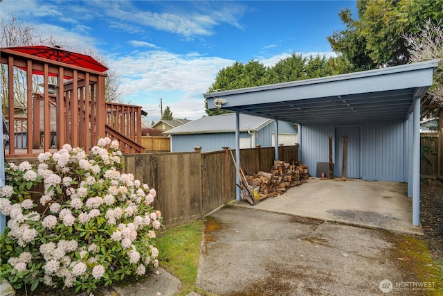 view of vehicle parking with a detached carport, concrete driveway, fence, and stairs