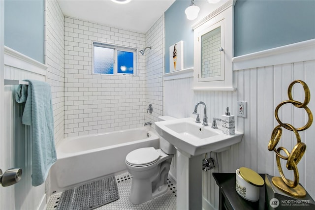 bathroom with tile patterned floors, toilet,  shower combination, and wainscoting