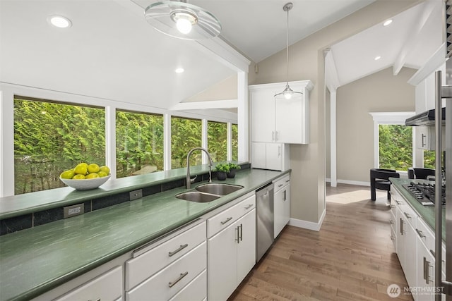 kitchen featuring white cabinets, a sink, lofted ceiling, and stainless steel appliances