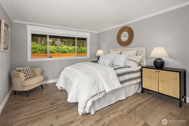 bedroom featuring wood finished floors, baseboards, and ornamental molding