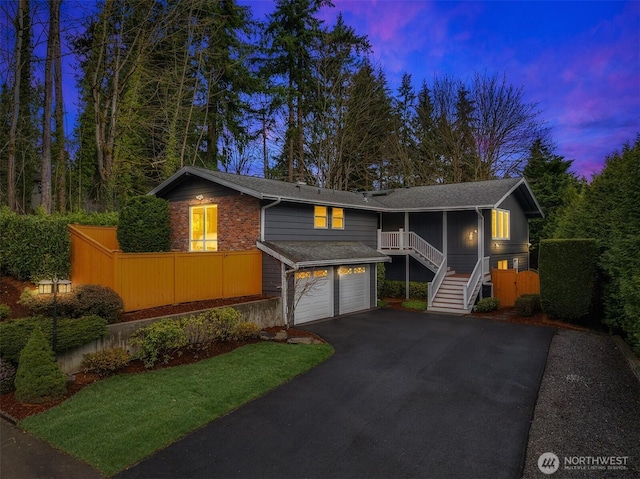split foyer home featuring a sunroom, an attached garage, stairway, brick siding, and driveway