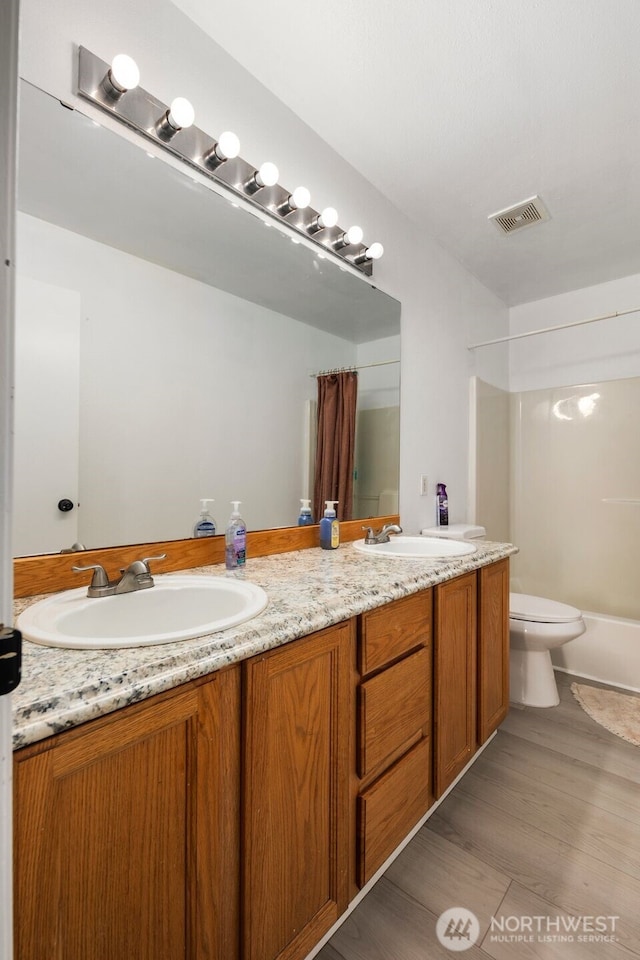 21813 43rd Avenue Ct E, Spanaway, WA 98387 - bathroom featuring double vanity, toilet, shower / bath combination, and wood finished floors