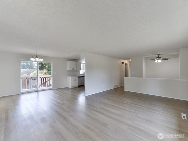 unfurnished living room with visible vents, ceiling fan with notable chandelier, a textured ceiling, and light wood-style flooring