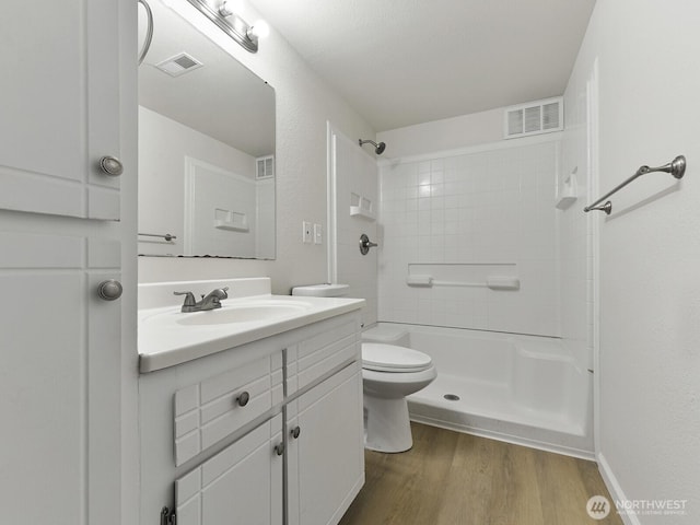 full bath featuring toilet, wood finished floors, visible vents, and walk in shower