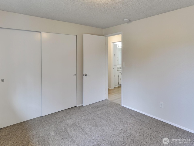 unfurnished bedroom with light colored carpet, a closet, and a textured ceiling