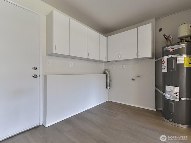 washroom featuring cabinet space, strapped water heater, wood finished floors, and baseboards