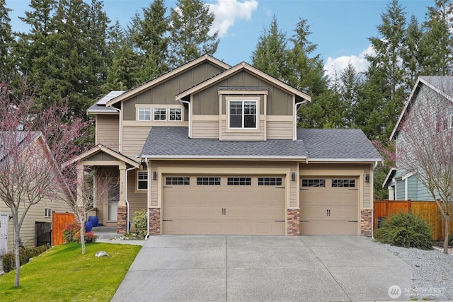 craftsman-style home featuring board and batten siding, fence, concrete driveway, stone siding, and an attached garage