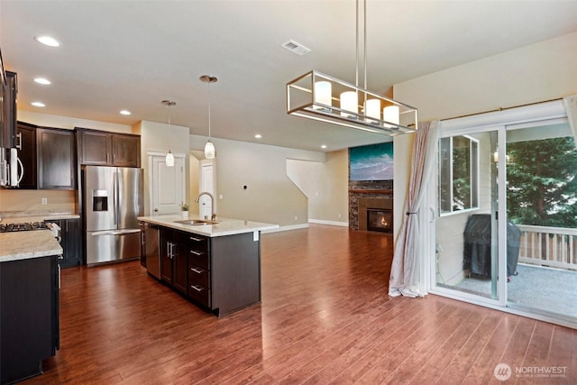 kitchen featuring visible vents, a sink, dark wood finished floors, dark brown cabinetry, and appliances with stainless steel finishes