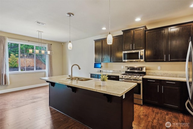 kitchen featuring a sink, dark wood-type flooring, a breakfast bar, and stainless steel appliances