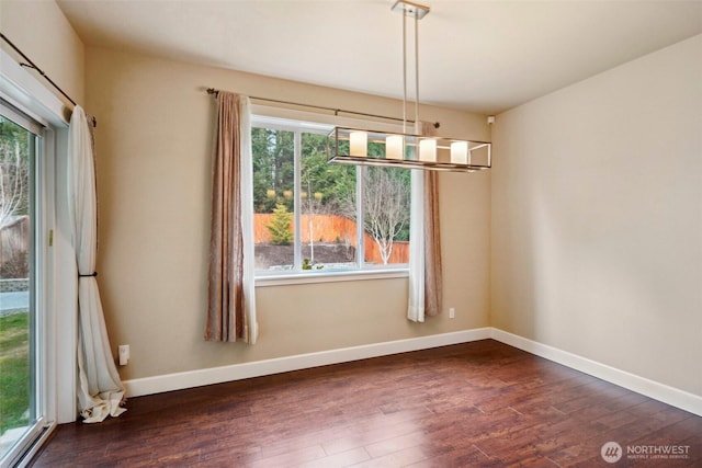 unfurnished dining area with dark wood finished floors and baseboards