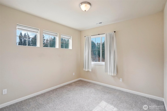 spare room with carpet, visible vents, and baseboards