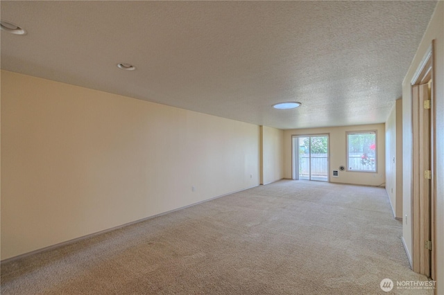 spare room featuring light colored carpet, baseboards, recessed lighting, and a textured ceiling