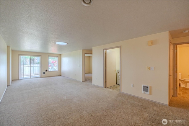 unfurnished room featuring a textured ceiling, visible vents, light colored carpet, and baseboards