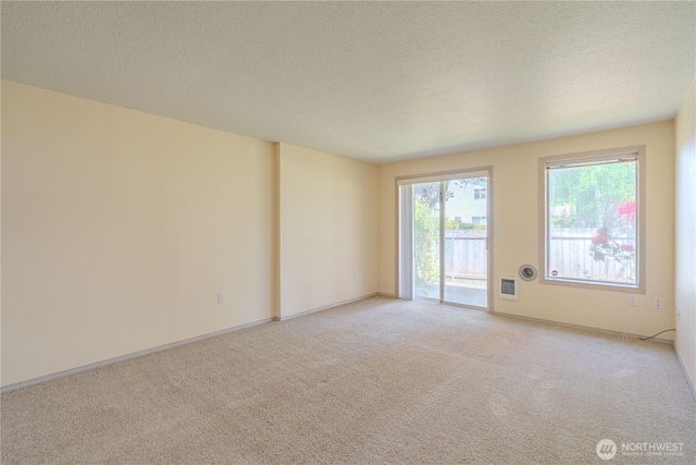 spare room featuring a textured ceiling, light carpet, and baseboards