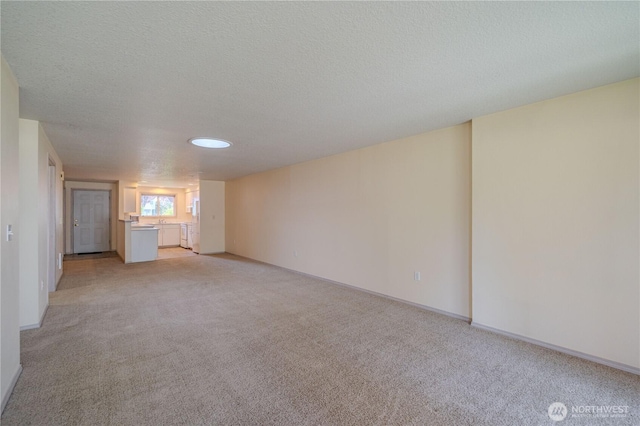 interior space with a textured ceiling, light carpet, and baseboards