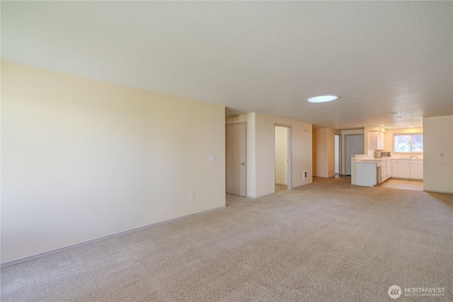 unfurnished living room featuring baseboards, light carpet, and a textured ceiling