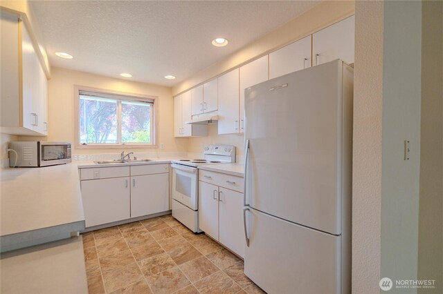 kitchen with recessed lighting, a sink, under cabinet range hood, white appliances, and light countertops