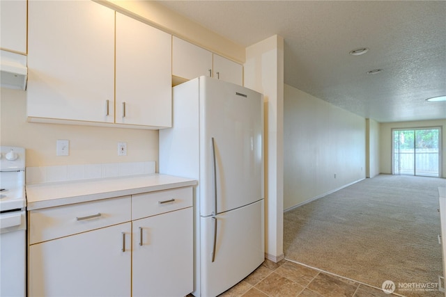 kitchen with white appliances, light colored carpet, a textured ceiling, light countertops, and open floor plan