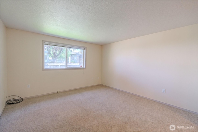 empty room with a textured ceiling and light colored carpet