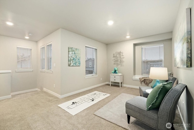 living area featuring recessed lighting, baseboards, and light colored carpet
