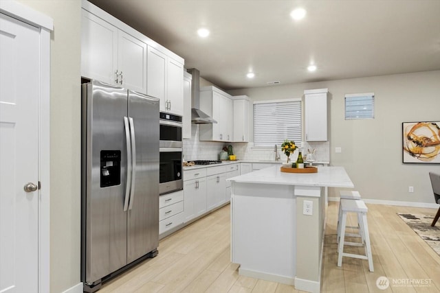 kitchen with a kitchen island, backsplash, appliances with stainless steel finishes, a sink, and light wood-style flooring