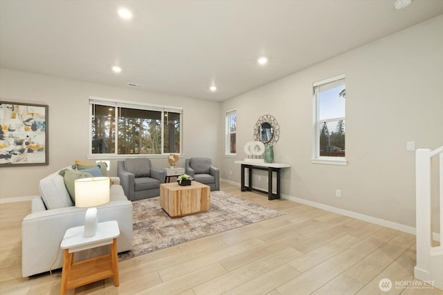 living room with light wood-style floors, recessed lighting, baseboards, and plenty of natural light
