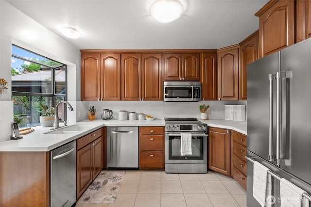 kitchen with light countertops, brown cabinets, appliances with stainless steel finishes, light tile patterned flooring, and a sink