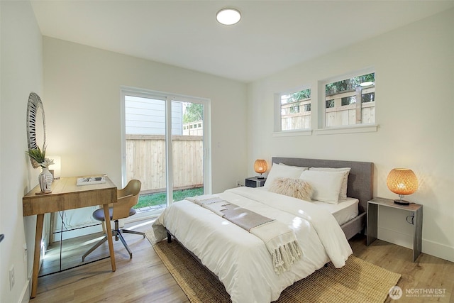 bedroom with wood finished floors, baseboards, and access to outside