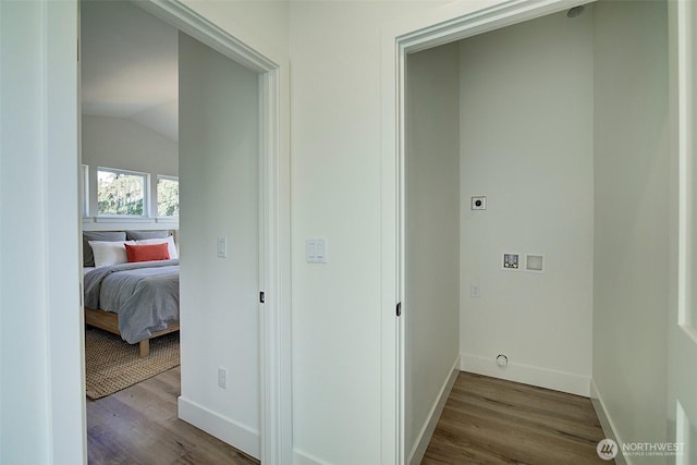 hallway featuring vaulted ceiling, dark wood-style floors, and baseboards