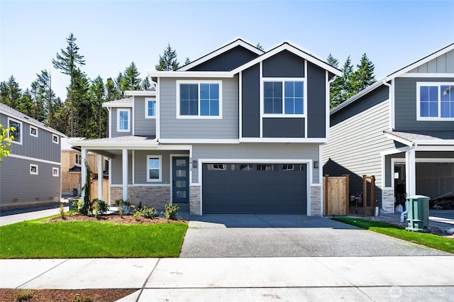 2406 SW Ridgeway Dr, Oak Harbor, WA 98277 - view of front of house with driveway, stone siding, a garage, and covered porch