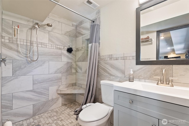 full bath with visible vents, toilet, tiled shower, and vanity