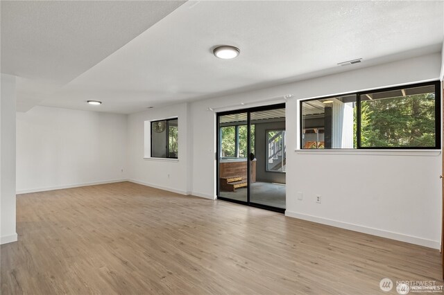 spare room with baseboards and light wood-type flooring