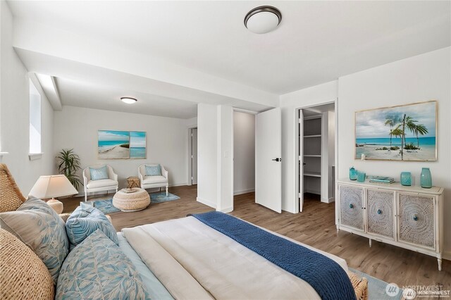 bedroom featuring a walk in closet, baseboards, and wood finished floors