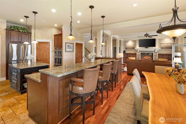 1935 False Bay Dr, Friday Harbor, WA 98250 - kitchen with a ceiling fan, stainless steel appliances, a center island, a lit fireplace, and pendant lighting