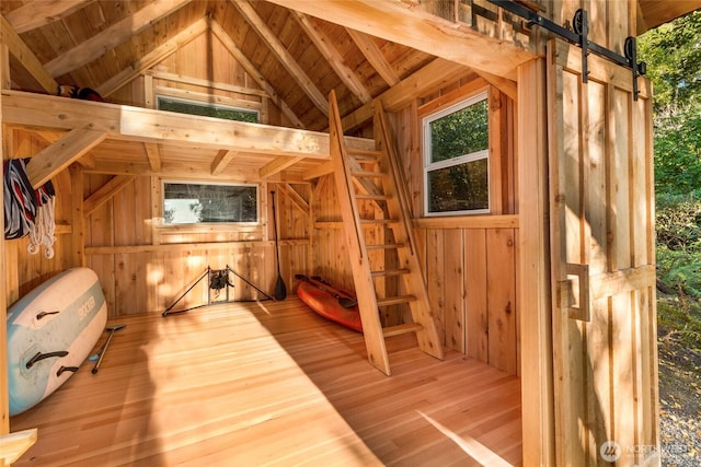 1935 False Bay Dr, Friday Harbor, WA 98250 - unfurnished bedroom with wood walls, vaulted ceiling, wood finished floors, a barn door, and wooden ceiling